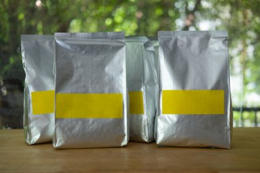 Bir grup kavrulmuş kahve çekirdeği alüminyum folyo sehpada, ahşap sehpanın üzerinde.