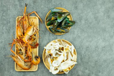 Izgara karides, ızgara kalamar ve ahşap tabakta haşlanmış midye. Üst görünüm