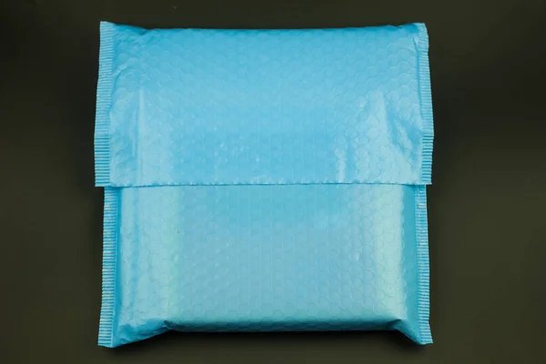 黒い背景に何かがぶつかったり衝撃的な防止のためにバブルラップで作られた青い封筒 — ストック写真