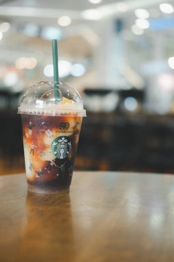 Bangkok, Tayland - 15 Kasım 2021: Yuzu Cold Brew yeniden kullanılabilir bir bardakta ve ahşap masa üzerinde özel bir 50. yıl dönümü tasarımı