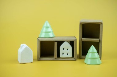 Küçük seramik beyaz ev ve sarı arka planda seramik Noel ağacı olan Noel süsleri.