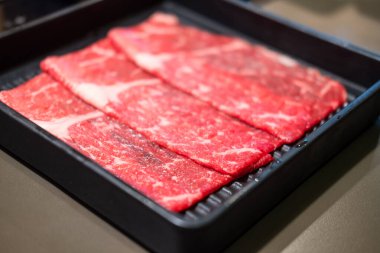 Shabu Shabu için siyah tepside çiğ et dilimi.