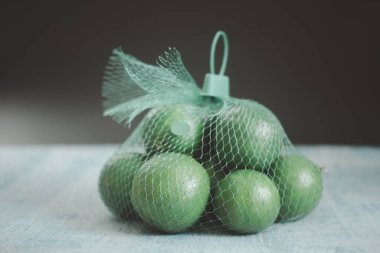 Yeşil bir ağ torbasında bir grup yeşil limon. Kapat.