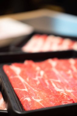 Barbekü için dilimlenmiş çiğ et veya Japon sukiyaki ve shabu shabu. Taze çiğ, ince dilimlenmiş et, seçici odaklanma.