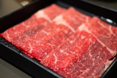Shabu Shabu ya da Japon sukiyaki 'si için hazırlanmış taze ve çiğ domuz eti tepsisini kapatın.
