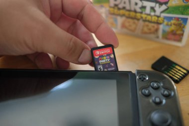 Bangkok, Tayland - 19 Aralık 2021: Mario Party Superstars video oyunu kartuşunu Nintendo Anahtarı konsoluna yerleştiren adam. 2021 'deki yeni versiyon.