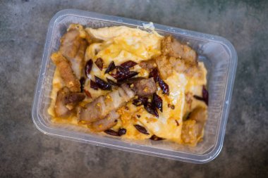Stir-fried pork with salt garlic and pepper served on scrambled eggs put in box. Top view