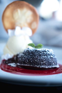 Chocolate fondant with strawberry sauce on plate, close up