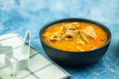Thai meal of panang curry with pork in black bowl.