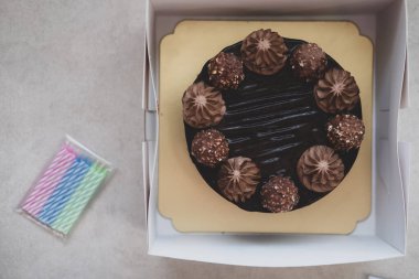 Kutuda lezzetli çikolatalı pasta ve mutlu yıllar için mum.