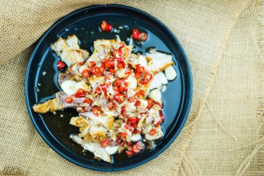 Limonlu sarımsaklı çıtır domuz sosu ve siyah tabakta acı sos salatası.