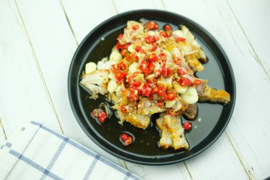 Limonlu sarımsaklı çıtır domuz sosu ve siyah tabakta acı sos salatası.