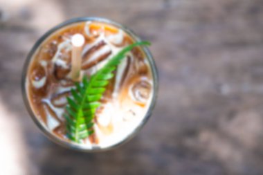 Arka planda bulanıklık ve ahşap masada buzlu kahvenin üst görüntüsü