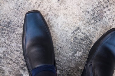 Adamın bacaklarına ve siyah deri ayakkabılarına yakından bak..