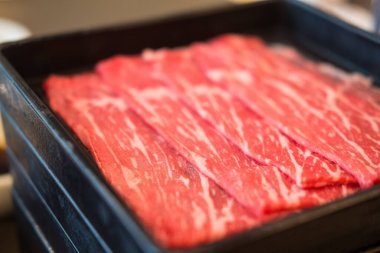 Sukiyaki ve Shabu için siyah tepside servis edilen taze çiğ et.