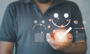 Modern adam gülümseyen bir ifade veriyor, akıllı telefondan olumlu eleştiri alıyor. Memnuniyet araştırmaları cep telefonundan yapılıyor. Ön manzara. Müşteri konsepti tecrübe eder.