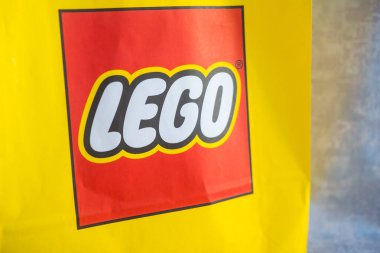 Bangkok, Samutprakarn - 19 Şubat 2022: Müşteri oyuncak alırken Lego mağazasından sarı kağıt bir çanta aldı. Üzerinde LEGO logosu olan sarı kağıt alışveriş torbaları.