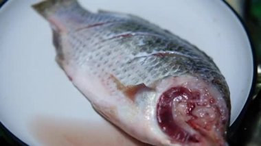 Tilapia 'yı bir tabağa koyuyor, şef balığı balık kemiğine kadar kesmek için bıçak kullanıyor.. 