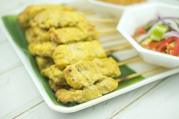 Pork satay eating with peanut sauce pickles which are cucumber slices, onions in vinegar