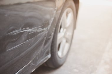 Arabadaki hasarlı kapıların seçici odak noktası. Çizikler, kazanın ve çarpışmanın sonucu olarak boyanın soyulması. Yakın plan..