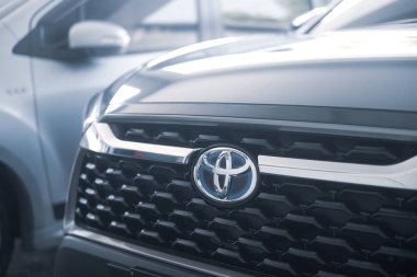 Samut Prakan, Tayland - 22 Mart 2022: Toyota 'nın Hybrid modellerinde kullandığı mavi arka planlı özel marka logosunu kapatın. 1.8 litre hibrit motorlu yepyeni Toyota Corolla Cross arabasının ön görüntüsü