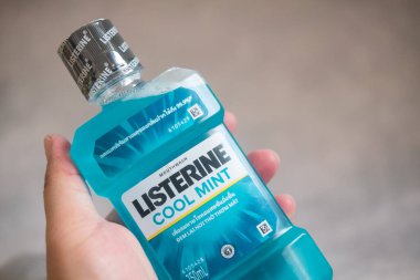 Samut Prakan, Tayland - 22 Mart 2022: Bir adamın eli Listerine gargara şişesini tutuyor. Listerine antiseptik gargara ürünüdür..