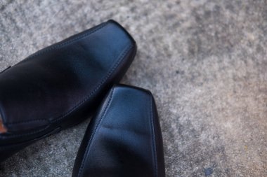 Çimento arka planında bir çift siyah ayakkabıyı kapat.