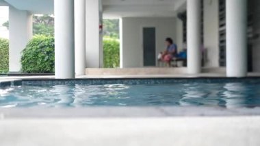 Tatil günlerinde dinlenmek için oteldeki mavi su havuzu ya da sandalyede oturan kadının bulanık arka planıyla seyahat etmek.