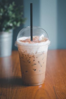 Masadaki plastik bardakta buzlu kapuçino. Paketlemeye hazırız. Favori kafein içeceği manusu. Sütlü ve sütlü..