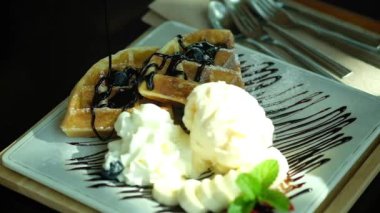 Waffle 'ların üzerine dondurmayla şurup dökmek. Yavaş çekim. 