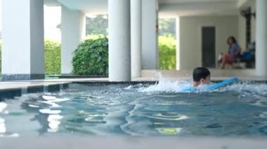 Açık havuzun açık mavi sularında oynayan çocuk, yavaş çekim.