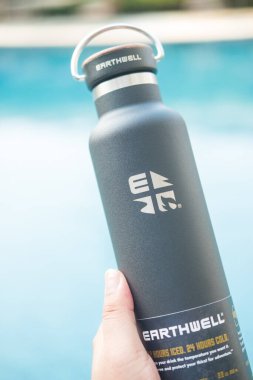 Bangkok, Tayland - 23 Nisan 2022: Ahşap kapaklı ve saplı siyah parlak metal su şişesi, iyi hissettirir, kavramak için yapılır. Dünya markasının ürünleri.