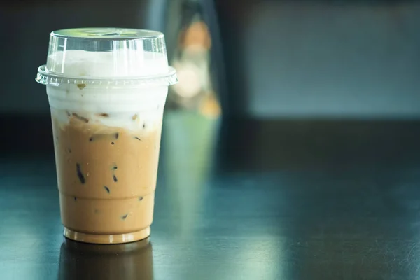 Iced Mocha coffee in a plastic cup on a wooden table at the cafe with copy space