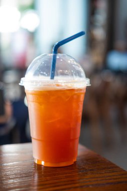 Ahşap masada plastik cam içinde greyfurt sodası.