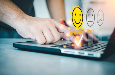 Müşteri, gülümseyen mutlu yüz ikonu üç yıldızın değerlendirme puanı için bilgisayarı kullanır. Müşteri deneyimi, geri bildirim ve memnuniyet anketi kavramı.