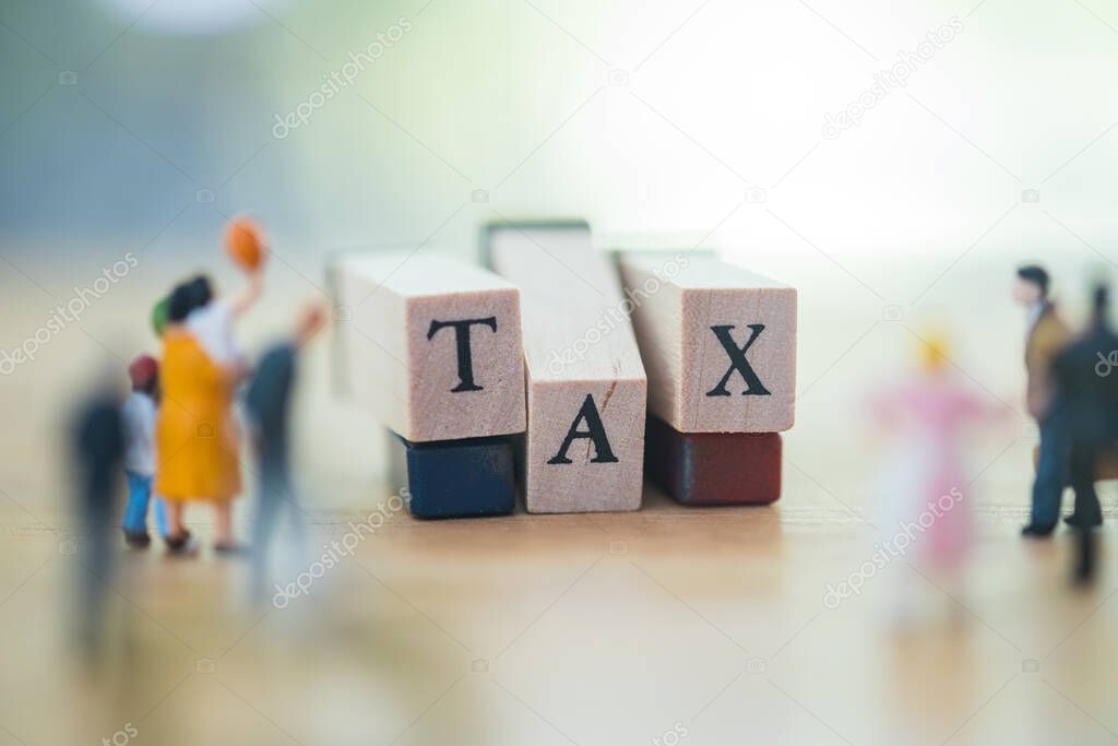 Wooden blocks with the word TAX with miniature people. Taxes and taxation. The tax burden, bank account balance payment, income  for expenses