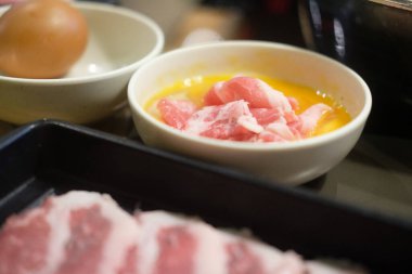 Japon yemeği Sukiyaki pişirmek için çiğ yumurtaya sığır eti dalışı.