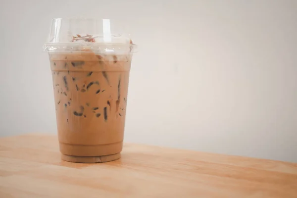 Iced mocha coffee in take away glass topped with milk foam cream at cafe