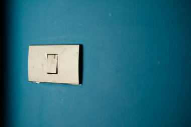 Mavi çimento duvar arka planında beyaz ışık düğmesi. Elektrik tasarrufu. Boşluğu kopyala.