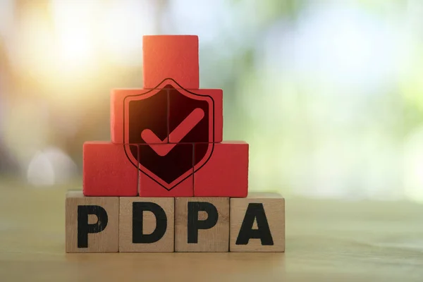 Shield with check mark icon on red wood placed block on PDPA word written on wood block. Protection from data theft privacy.