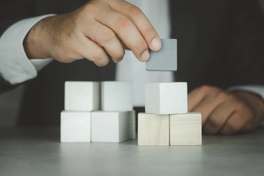 Hand putting wood cube on top of wood block stacking. Business growth to success. Crisis management