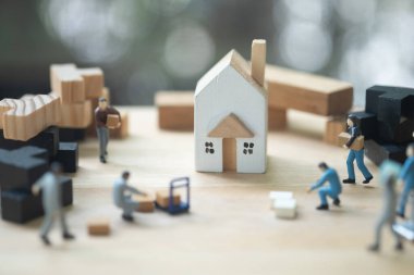 Minyatür işçi hareketi evden eve taşınıyor. Ahşap evde seçici odaklanma. Ev taşıma konsepti veya inşaat konsepti, ev sigortası ve bakım.