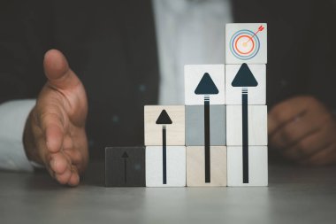 Businessman show wooden blocks with arrow bar chart graphic arranged in stair shape point to target. Goals and planning for success in the marketing business, achieve the objective concept.