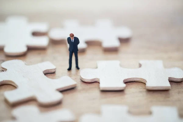 Businessman standing and jigsaw puzzle pieces thinking, using as thinking business plan and how to solve problem strategy planning concepts