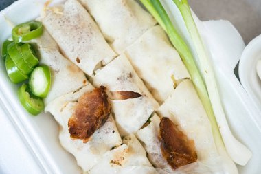 Yengeç etiyle kaplanmış taze Asya böreği ve taze soğan, köpük kutusunda yeşil biber..