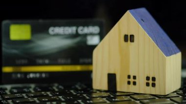 Home and black credit card on a computer keyboard. Slow-motion