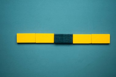 A row of empty four yellow wood block rectangle shape with one black wood block in the middle