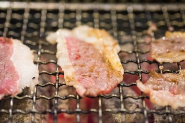 Half-cooked sliced beef on the grill stove. Yakiniku buffet. Selective focus