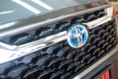 Samut Prakan, Thailand - August 6, 2022 : Close up special brand logo with blue background used by Toyota in Hybrid models. Front view of All-new Toyota Corolla Cross car with 1.8 litre hybrid engine