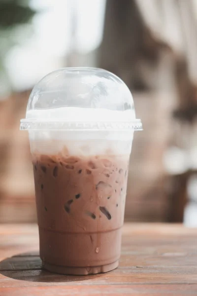 Iced Mocha coffee in take home plasttic cup on table with outdoor background